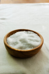 Fototapeta na wymiar Sea coarse salt in a wooden bowl on the table. Natural resource. Salt is suitable for cooking and beauty treatments. Vertical orientation. Copy space. Selective focus