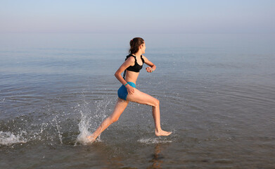 athletic girl runs fast on the water by the sea during daily training