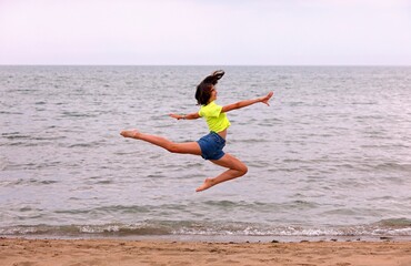 leap of the deer called BICHE performed to perfection by the athletic girl by the sea in summer