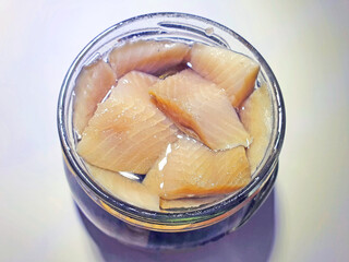 slices of slightly salted atlantic herring in a glass jar on a whitebackground	

