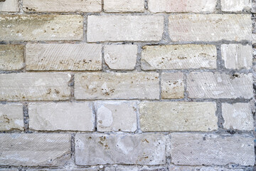 An old damaged wall made of white bricks as a background