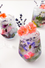 Refreshing cold drink with frozen flowers, cornflowers and geraniums, osteosperum and lavender and carnation