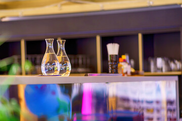 Two glass carafes of water stand on a bright bar counter