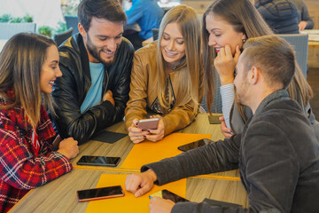Group of friends watching mobile phones and having fun