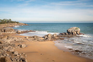 Fototapeta na wymiar Beautiful scenic view of a rocky beach on a day with blue sky and clouds, Noja, Cantabria, Spain