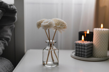 Home aroma fragrance diffuser and burning candles on bedside table in the bedroom. Interior elements.