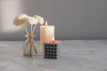 Home aroma fragrance diffuser and burning candles on marble background. Interior elements.