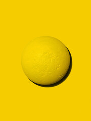 Yellow textured ball isolated on yellow background. Art or creativity. Pattern or background image