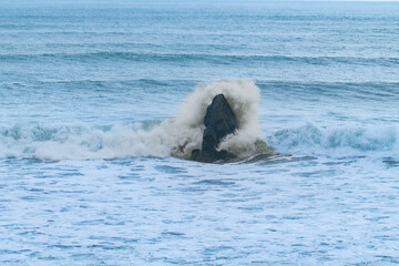 One rock with waves breaking around it