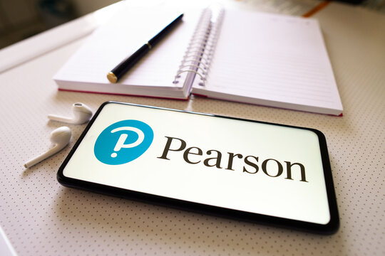 July 1, 2022, Brazil. In this photo illustration the Pearson Education logo seen displayed on a smartphone next to a book, pen and headphones.