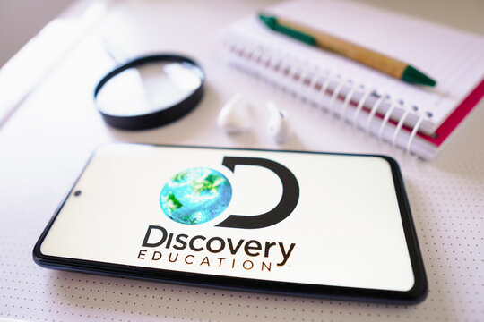 June 30, 2022, Brazil. In this photo illustration the Discovery Education logo seen displayed on a smartphone next to a book with pen, headphones and a magnifying glass.