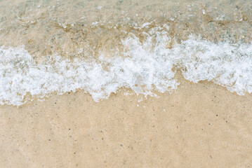 Close-up of wave washing onto sand beach shoreline