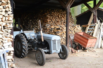 Working antique tractor amid chopped timber from wilnd-blown trees, 16th century Earlshall Castle, Leuchars, Fife, Scotland, July 2022, Open Gardens
