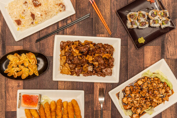 Set of oriental food dishes with panko battered prawns, fried wonton, rice with ham, rice roll with bluefin tuna and beef with bamboo and mushrooms