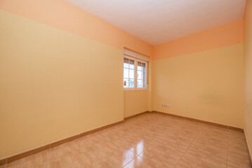 Empty room with light brown stoneware floor, two-tone yellow painted walls and white aluminum...