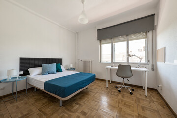 Fototapeta na wymiar large bedroom with double bed, blue metal nightstands, large window and white study table below
