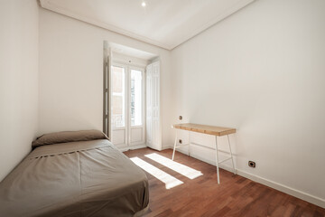 Fototapeta na wymiar bedroom with single bed, metal and wood table and balcony with windows and wooden shutters