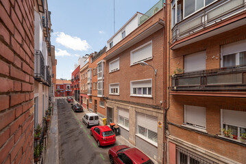 Narrow street with low-rise buildings with clay brick facades with balconies and terraces