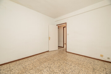 Empty room with old terrazzo floor, white walls and white painted wooden door