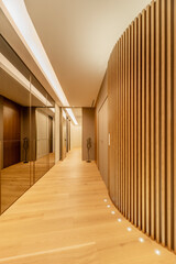 Corridor of a house with a wall covered with mirrors on one side and wooden slats on the other