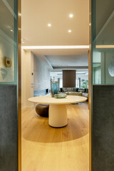 Hallway of luxury home with round table with vases, latticework walls and oak floor with glass and metal doors