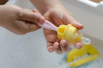 Washing baby nipples. Mother's hand washing the baby nipples