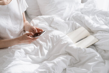 Woman using smartphone for surfing the web in bedroom - Powered by Adobe