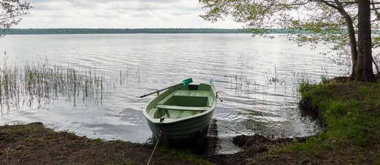 Small green boat anchored in forest lake. Scandinavia. Transportation, traditional craft,...