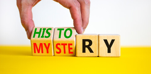 History versus mystery symbol. Concept words History and mystery on wooden cubes. Businessman hand. Beautiful yellow table white background. Business, History versus mystery concept. Copy space.