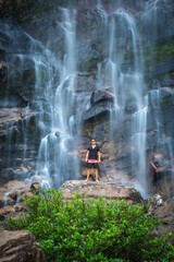 Beautiful view to man enjoying big natural wild waterfall
