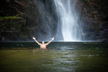Beautiful view to man enjoying big natural wild waterfall