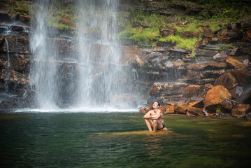Fototapeta na wymiar Beautiful view to man enjoying big natural wild waterfall