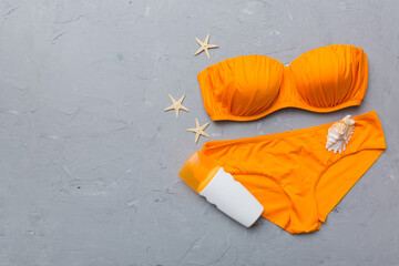 Woman swimwear and beach accessories flat lay top view on colored background Summer travel concept. bikini swimsuit, straw hat and seasheels. Copy space Top view