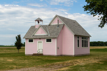 Fototapeta na wymiar Close up view of an old pink country school house exterior with bell tower, built in the 1800’s in the midwestern USA