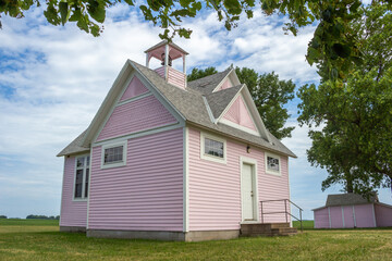 Close up view of an old pink country school house exterior with bell tower, built in the 1800’s in the midwestern USA