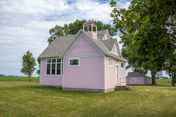 Close up view of an old pink country school house exterior with bell tower, built in the 1800’s in the midwestern USA