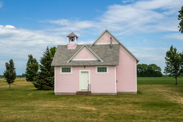 Fototapeta na wymiar Close up view of an old pink country school house exterior with bell tower, built in the 1800’s in the midwestern USA
