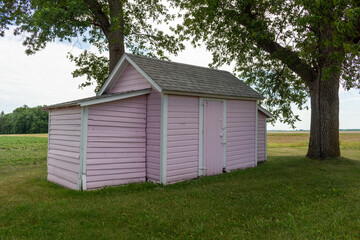 Close up view of an old pink painted storage shed built in the 1800’s in the midwestern USA