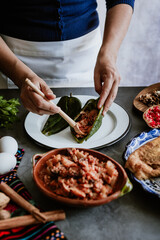 mexican woman hands preparing and cooking chiles en nogada recipe with Poblano chili and ingredients, traditional dish in Puebla Mexico