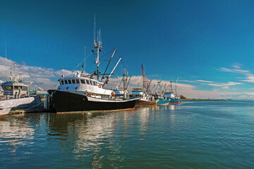 Fototapeta na wymiar Fishing Boats in Marina and a cloudy sky. This marina is located in the Steveston area of Richmond. The fishing village formed in this place was the first settlement on the territory of Richmond