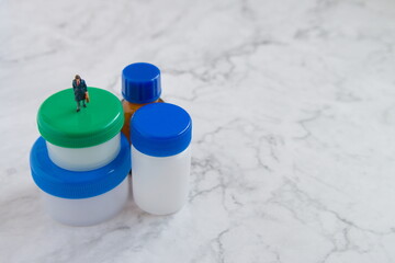 プラスチック容器と小瓶とミニチュア男ビジネスマンの左寄りの写真