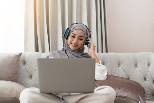 Asian Muslim Woman Having Video Teleconference On Her Laptop At Home, Online Learning Or Working From Home Concept