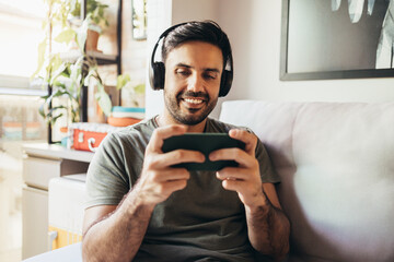 Man playing video game on smartphone in his living room