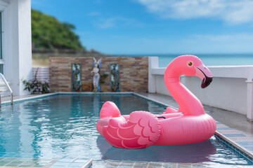 Pink inflatable flamingo on swimming pool. Concept for summer day © banphote