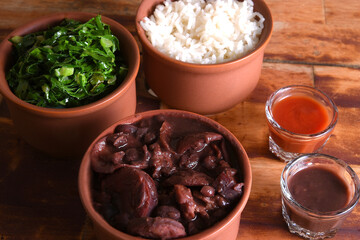 Feijoada typical Brazilian food, beans with pork bacon, orange rice and flour, chili sauce and crackling