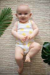 Adorable happy little baby girl sitting on furry carpet at home.