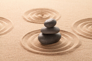 Fototapeta na wymiar stone on sand with zen pattern. meditation harmony concept.