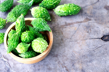 Bitter gourd vegetable in wooden bowl on old wood table backgrounds