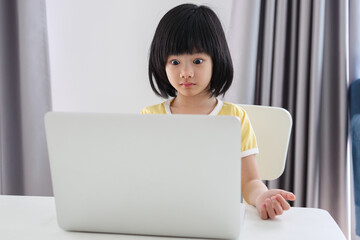 little asian girl student study online using laptop computer at home