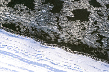 Arctic winter landscape in frozen bay. Floating ice floes in river on white frost bank. Beginning of glaze drift in reservoir, risk of navigation for vessel